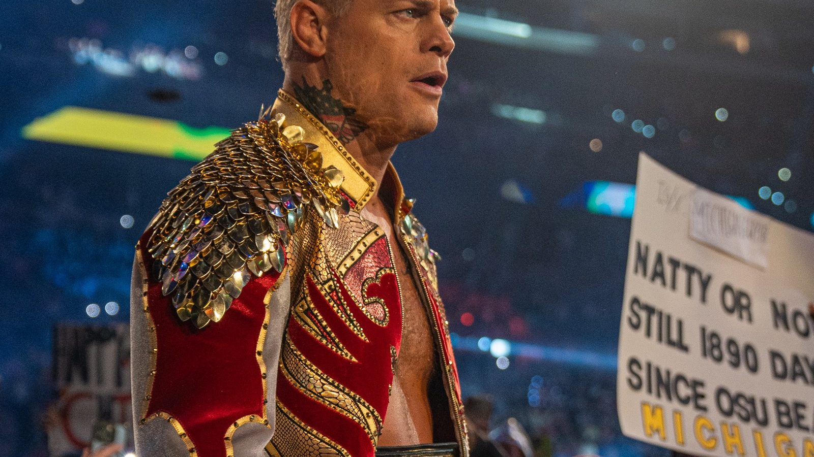 Cody Rhodes in a red and gold jacket carrying the WWE Championship belt through the crowd at the 2025 Royal Rumble