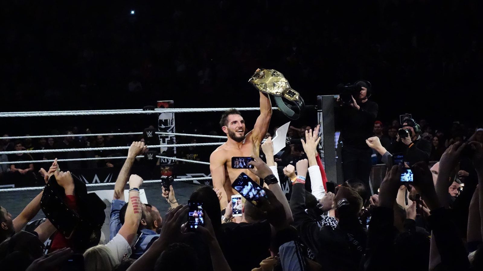 Johnny Gargano holds the NXT Championship belt above his head among fans at ringside after winning the vacant title at NXT TakeOver: New York on April 5, 2019