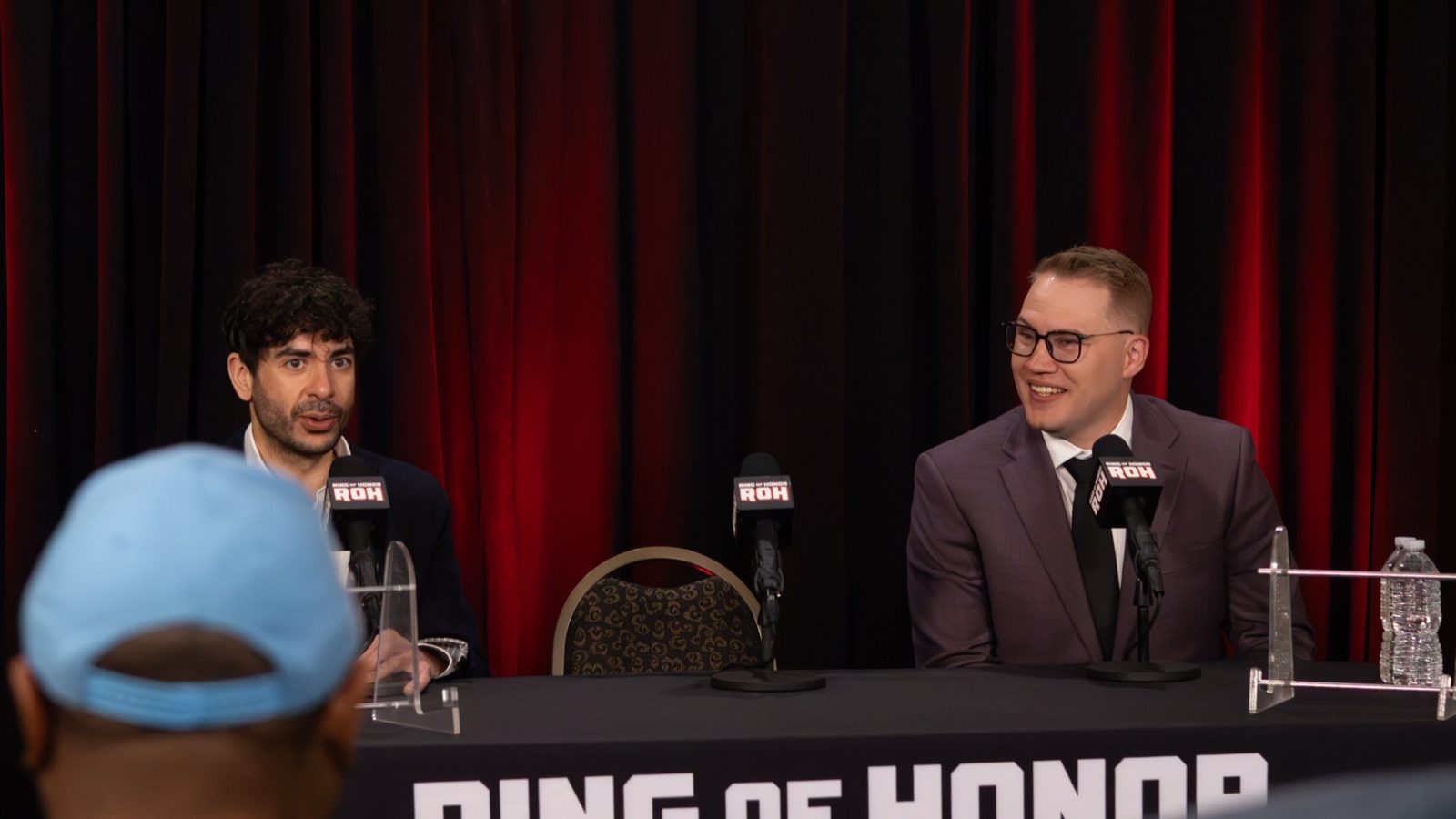 Tony Khan and Ian Riccaboni seated behind a Ring of Honor table at the Supercard of Honor 2026 press conference